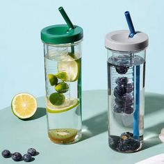 two glass cups with strawberries, lemons and blueberries in them sitting on a table