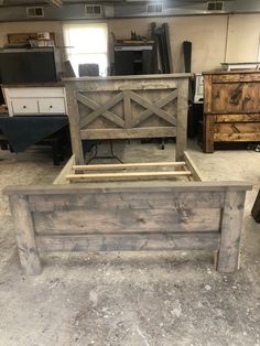 a bed frame made out of wood in a room with other pieces of furniture on the floor