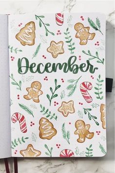 an open christmas planner with ginger cookies and candy canes on the cover, next to a pen