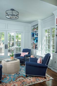 a living room filled with blue furniture and lots of bookshelves on the wall