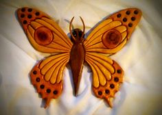 an orange and brown butterfly sitting on top of a white bed sheet with holes in it's wings