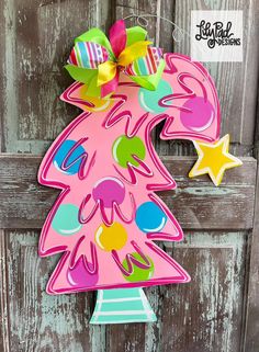 a pink christmas tree shaped door hanger with colorful decorations on it's side