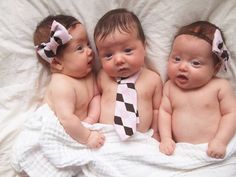 three babies wearing ties laying on top of a white blanket in the middle of a bed