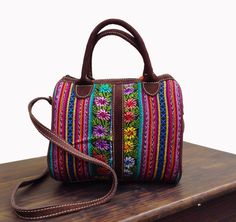 a multicolored handbag sitting on top of a wooden table next to a white wall