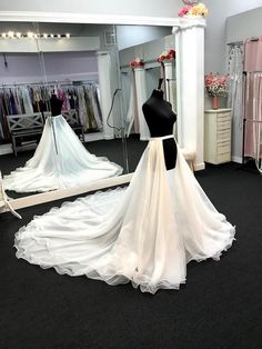 a wedding dress is displayed in front of a mirror and mannequins are behind it