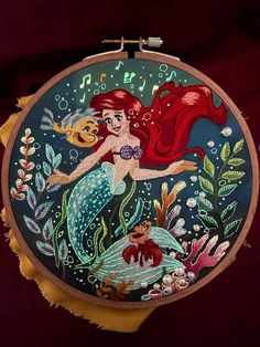 an embroidery project with a little mermaid holding a fish