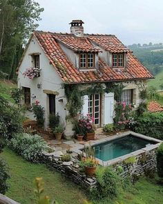 a house with a pool in the middle of it surrounded by greenery and flowers