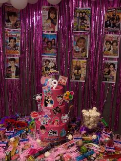 a pink birthday cake surrounded by balloons and streamers