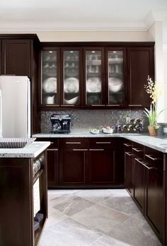 a kitchen with dark wood cabinets and marble counter tops, along with an island in the middle