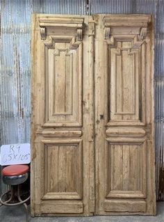 an old wooden double door sitting next to a chair