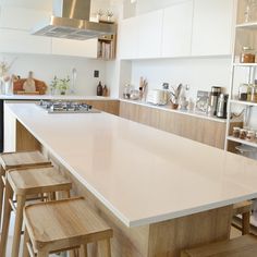 a kitchen with white counter tops and wooden chairs