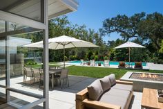 an outdoor patio with tables, chairs and umbrellas next to a swimming pool on a sunny day