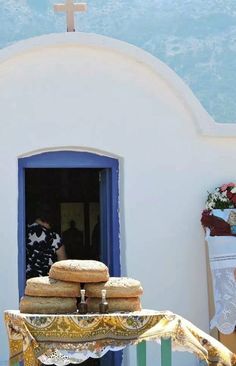 a table topped with lots of food next to a white church building and blue door