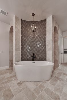 a bathroom with a tub and chandelier in the corner, along with marble flooring