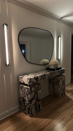 a marble console table and mirror in a room with hardwood floors, white walls and wood flooring