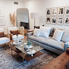 a living room with couches, chairs and pictures on the wall in it's center