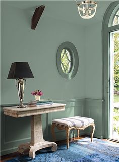 a room with a blue rug, table and two round mirrors on the wall above it