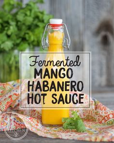 a glass bottle filled with mango habanero hot sauce sitting on top of a table