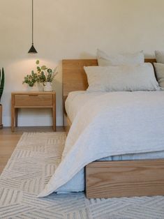 a bedroom with a bed, nightstands and plants on the side table next to it