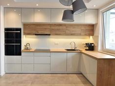 an empty kitchen with white cabinets and wooden counter tops is seen in this image, there are two pendant lights hanging from the ceiling