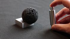 a person is holding a lighter next to an object on a table that looks like a lava ball