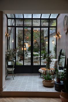 a room filled with lots of potted plants in front of a glass door that leads to a patio