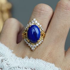 a close up of a person's hand wearing a ring with a blue stone