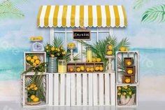 an image of a lemonade stand on the beach with yellow flowers and potted plants