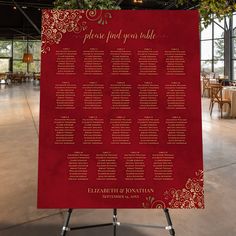 a red and gold wedding seating chart on a stand