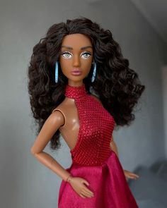 a barbie doll wearing a red dress and blue earrings with her hand on her hip