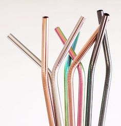 several different colored metal straws in a glass vase