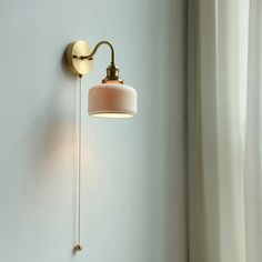 a wall light that is on the side of a white wall next to a window