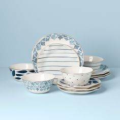 a blue and white dinnerware set on a light blue background with place setting in the middle