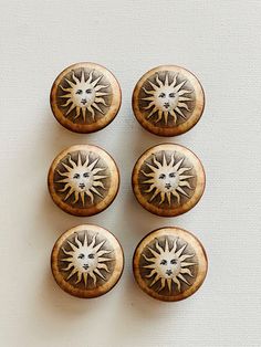 four wooden buttons with designs on them sitting on a white surface next to each other