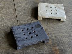 two pieces of cement sitting on top of a wooden floor next to each other with holes in them