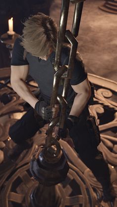 a man in black shirt working on a large metal object with chains attached to it