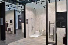 the interior of a modern bathroom with white marble walls and flooring, black framed glass partitions