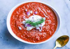 a white bowl filled with red sauce and garnished with onions