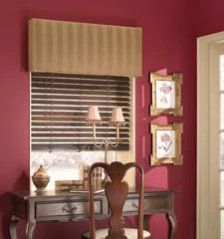 a desk and chair in a room with pink walls, striped blinds and wooden shutters