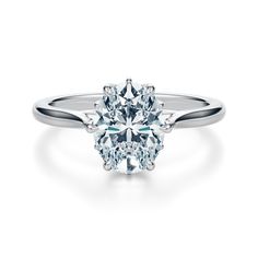 a white gold ring with an oval cut diamond in the center and two clawed shoulders