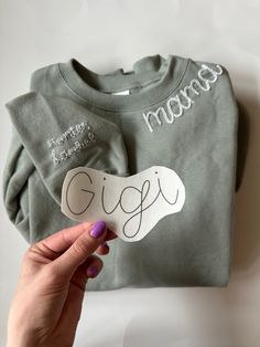 someone is holding up a t - shirt with the word gigi written on it