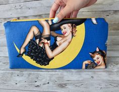 a woman's hand holding onto a blue and yellow purse with a pin up girl on it