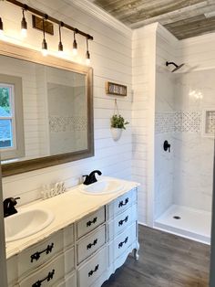 a white bathroom with two sinks and a large mirror above the bathtub is shown