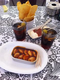 a table topped with drinks and food on top of a white plate covered in condiments