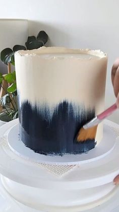 a person is decorating a cake with blue and white icing