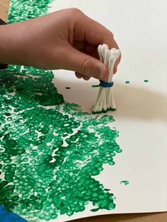 someone is painting green and white paint on paper