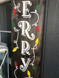 a wooden sign with the words merry written in white and red lights on it's side