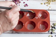 a person is using a pen to draw on an empty cupcake pan with muffins in it