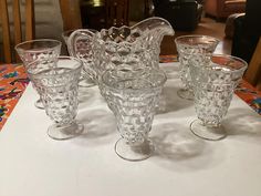 an assortment of glassware sitting on top of a white tablecloth covered dining room table