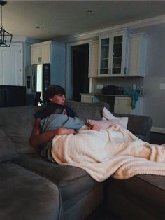 two people sitting on a couch in a living room with a blanket over their backs